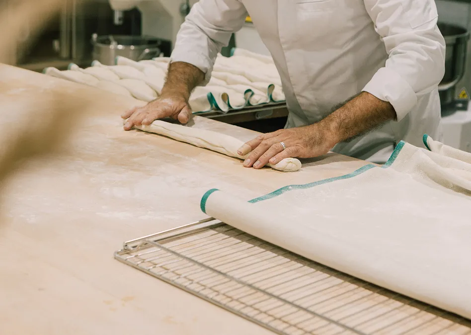 Boulanger façonnant des pâtons de pain sur un plan de travail fariné