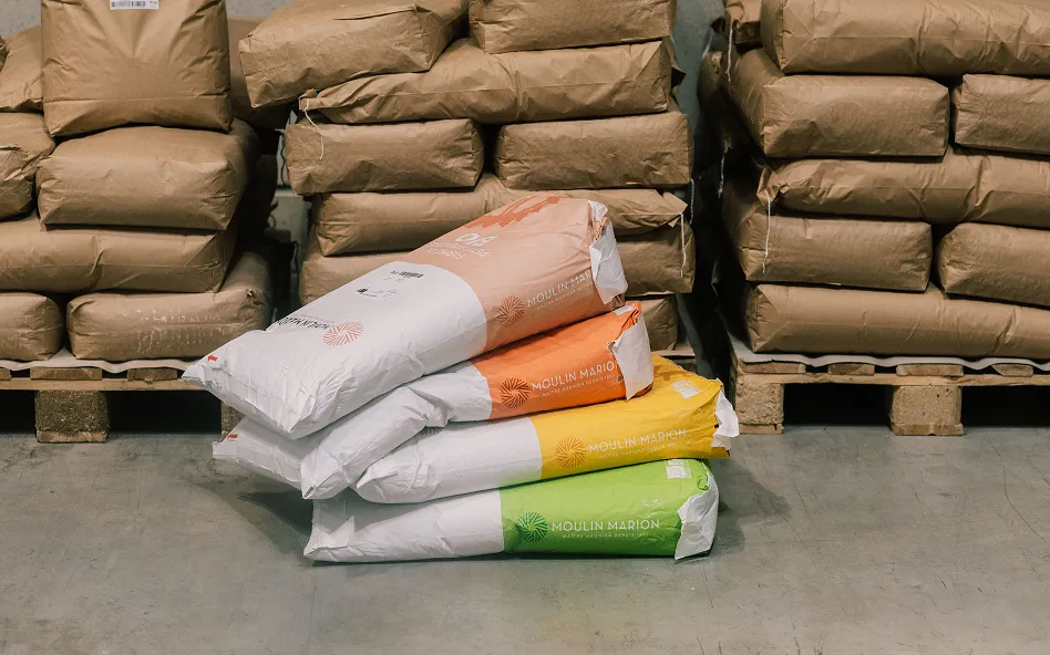 Pile de sacs de farine Moulin Marion de différentes gammes dans un entrepôt