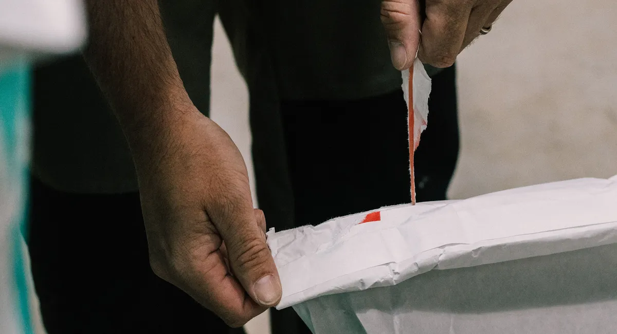 Mains ouvrant le sceau en papier d'un sac de farine