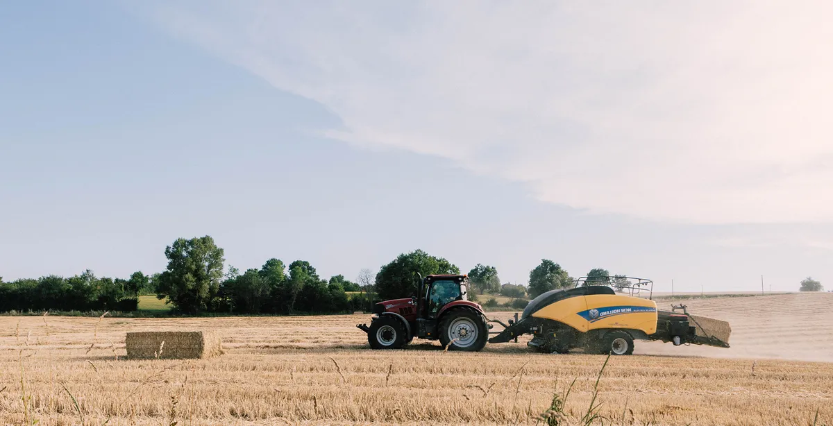 Tracteur et presse à balles récoltant la paille dans un champ moissonné