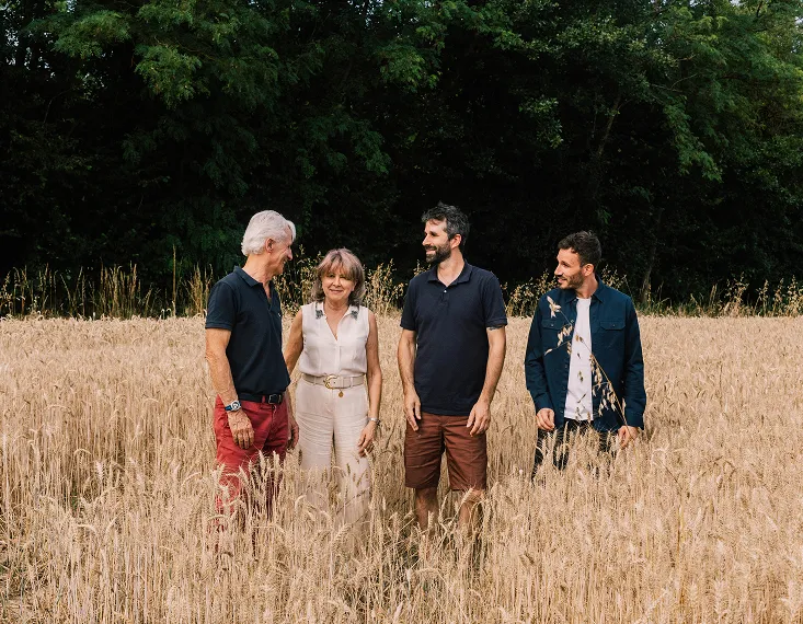Quatre personnes souriantes debout dans un champ de blé
